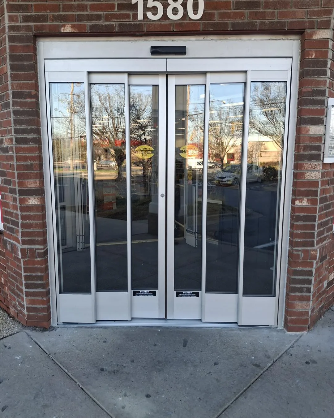 Newly installed Stanley automatic sliding glass doors on a brick storefront